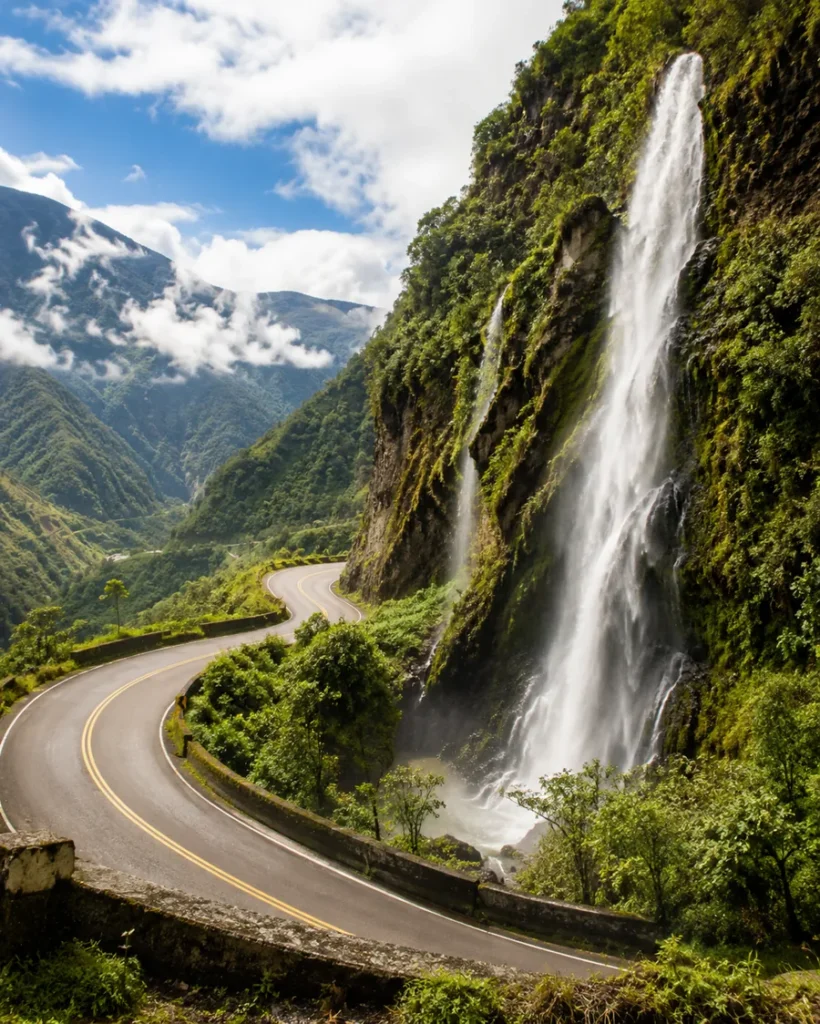 A stunning waterfall cascading down a mountain beside a winding road.