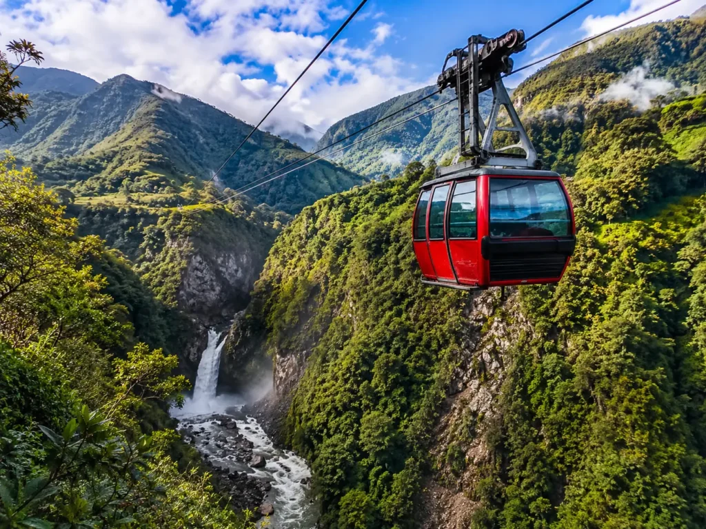Red cable car over lush green mountains and waterfall.